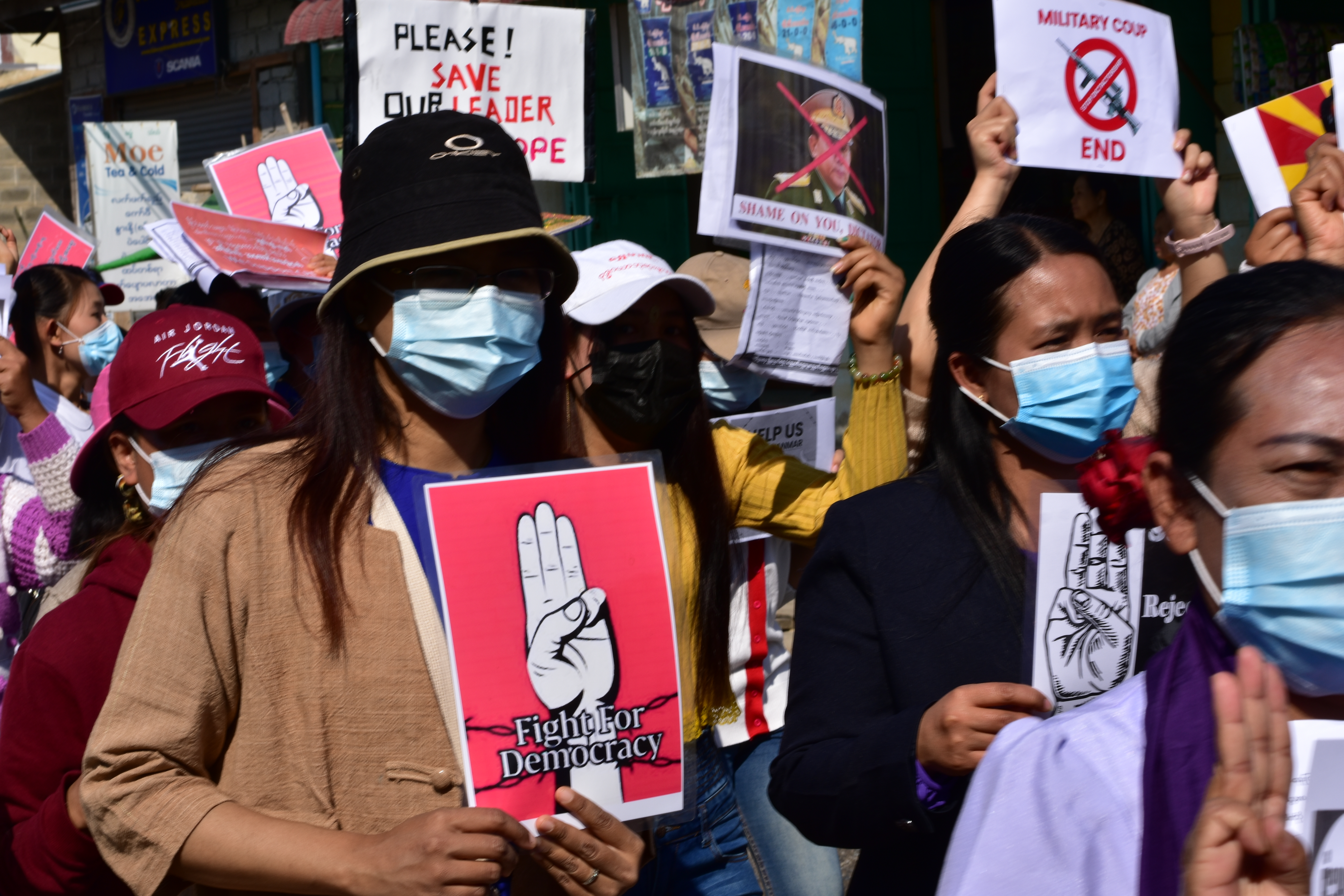 People in Myanmar holding signs in support of democracy at a protest against the military coup in February 2022