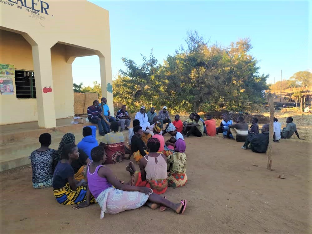 A group of people sitting on the ground deliberating