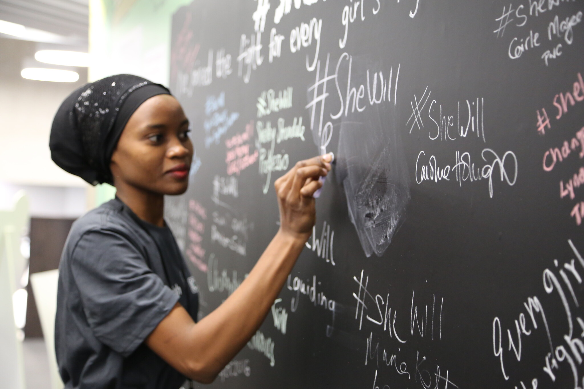 A delegate signs the #SheWill wall at the Girls' Education Forum, London, 7 July 2016