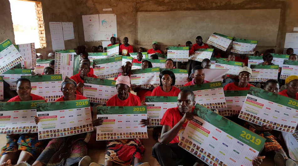 Group of people holding placards while sitting