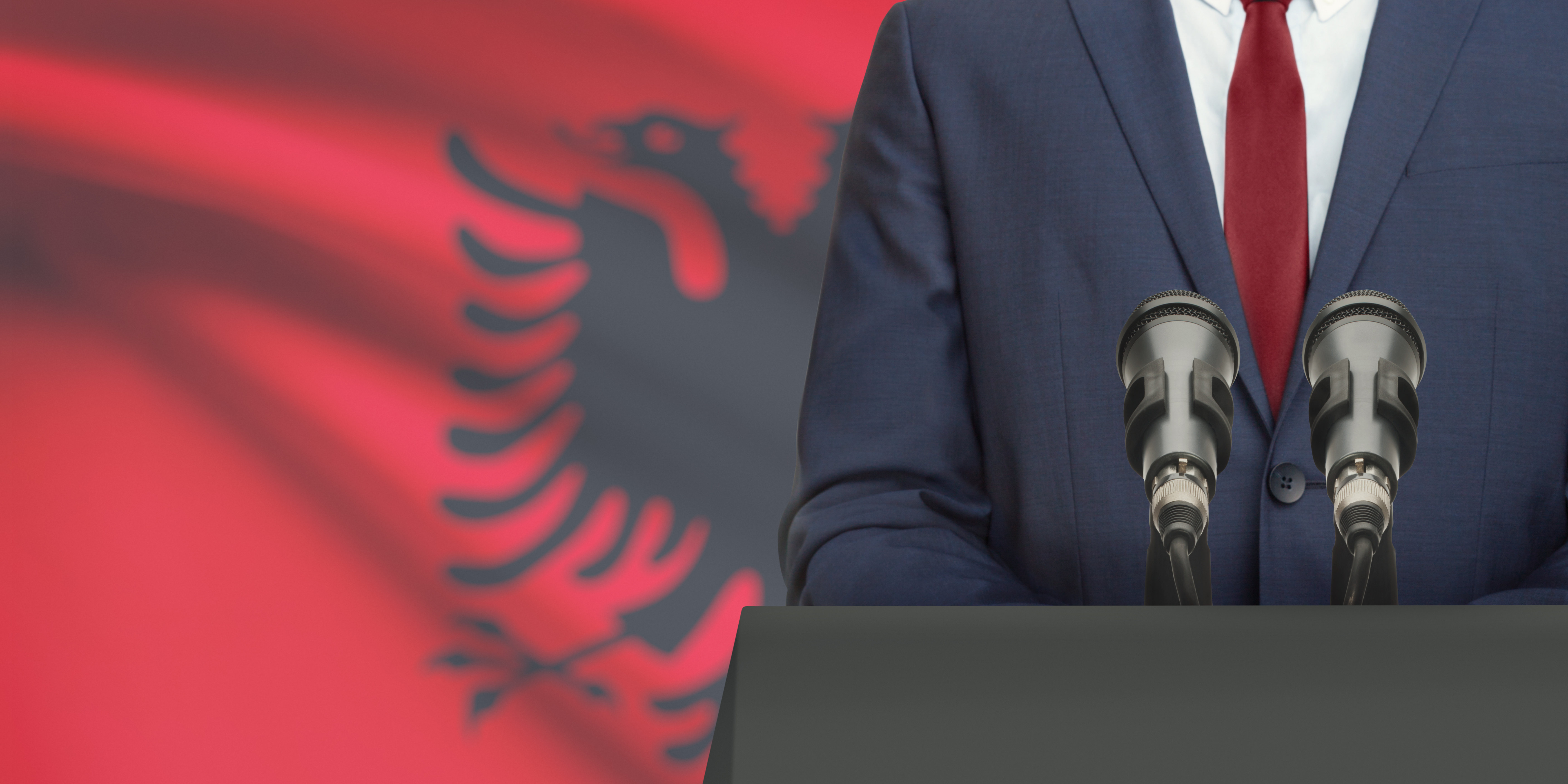 person standing in front of a microphone, albanian flag