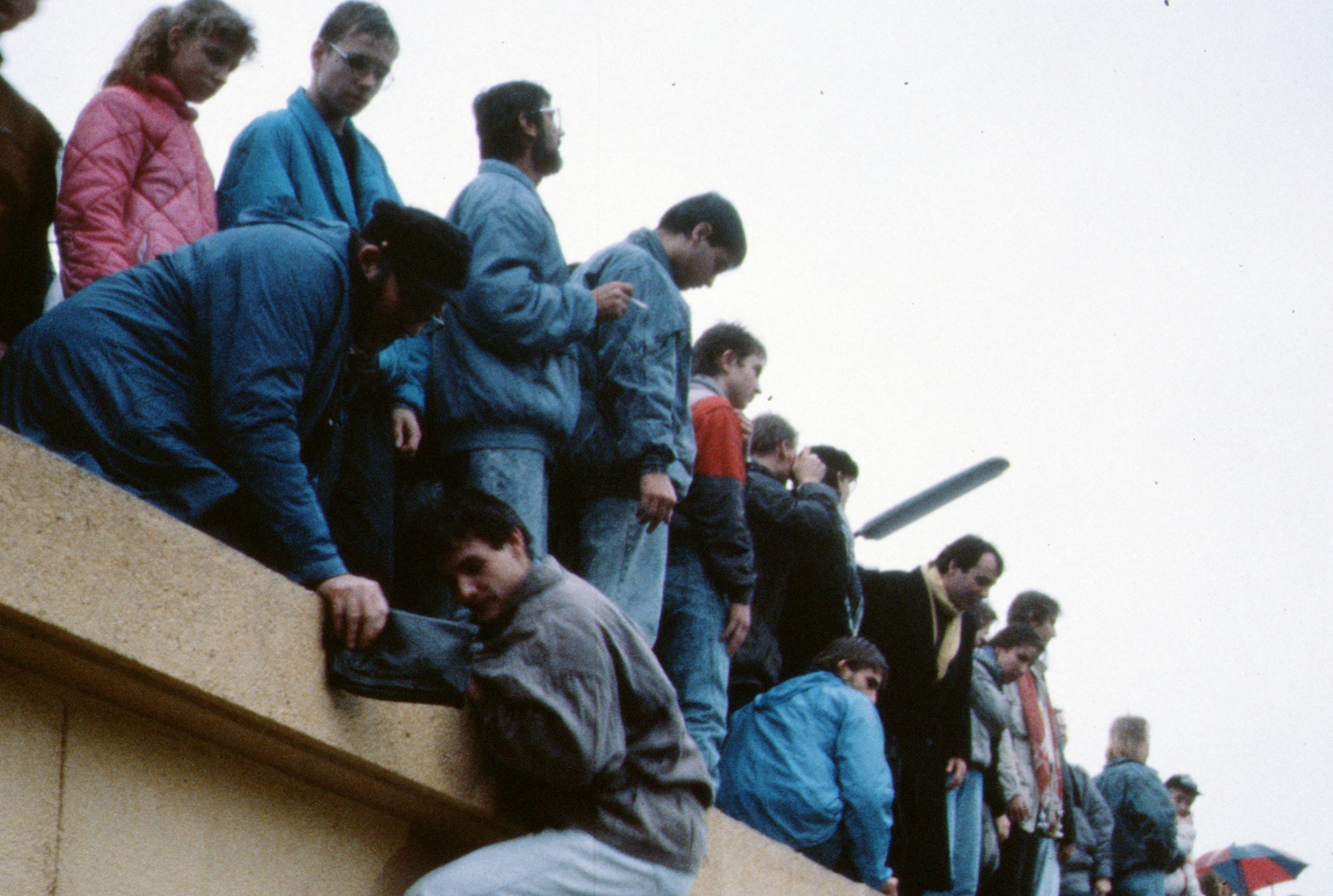 People climbing over the Berlin Wall