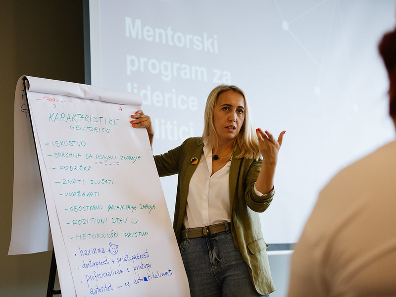 A woman standing next to a flip chart with writing in local language