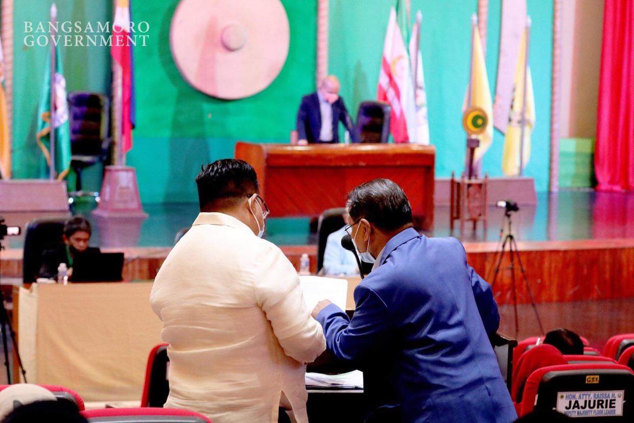 Two men examine a document in a session of the Bangsamoro Transition Authority