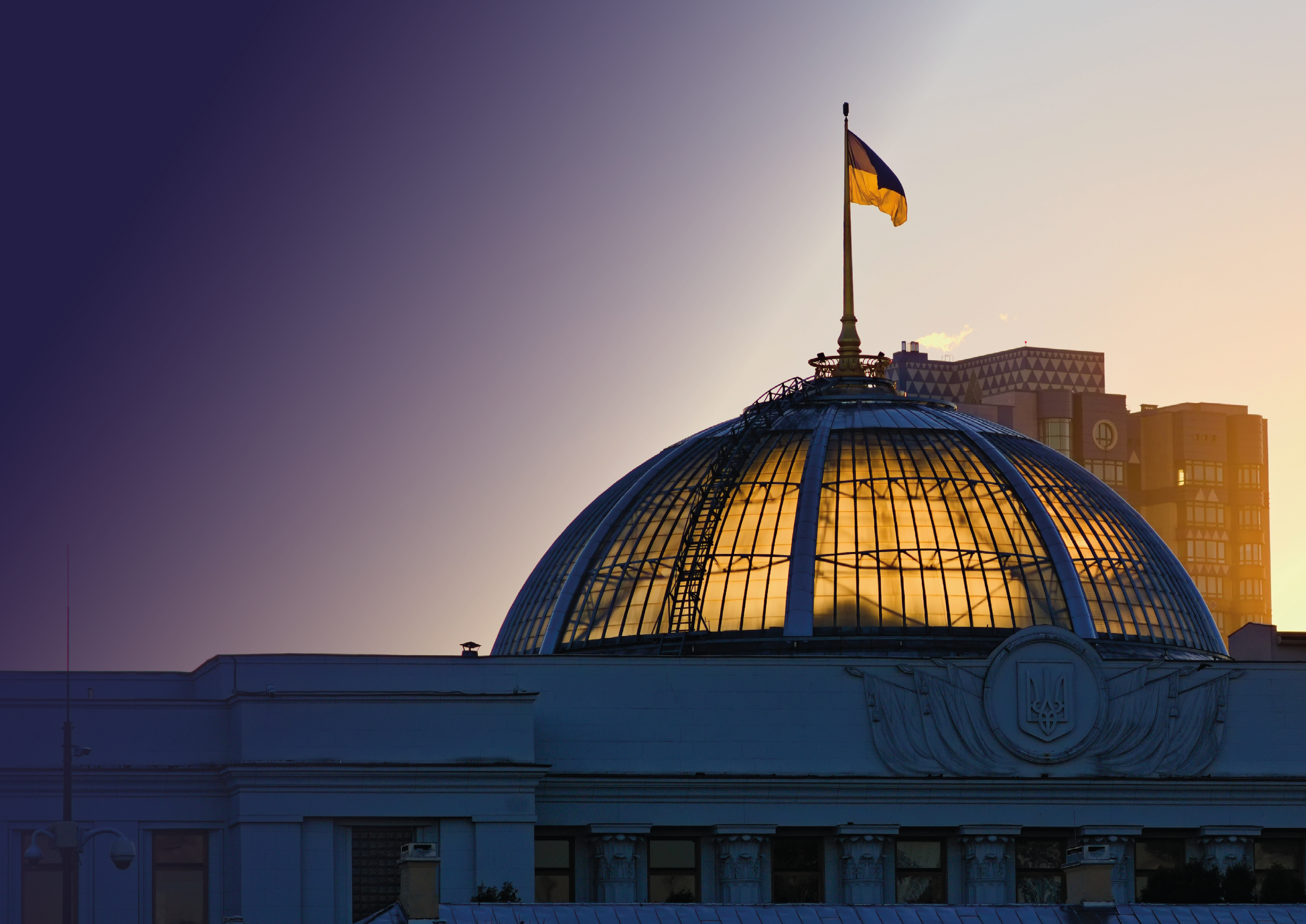 The sun coming through the dome of the Parliament of Ukraine, with the Ukrainian flag flying above 