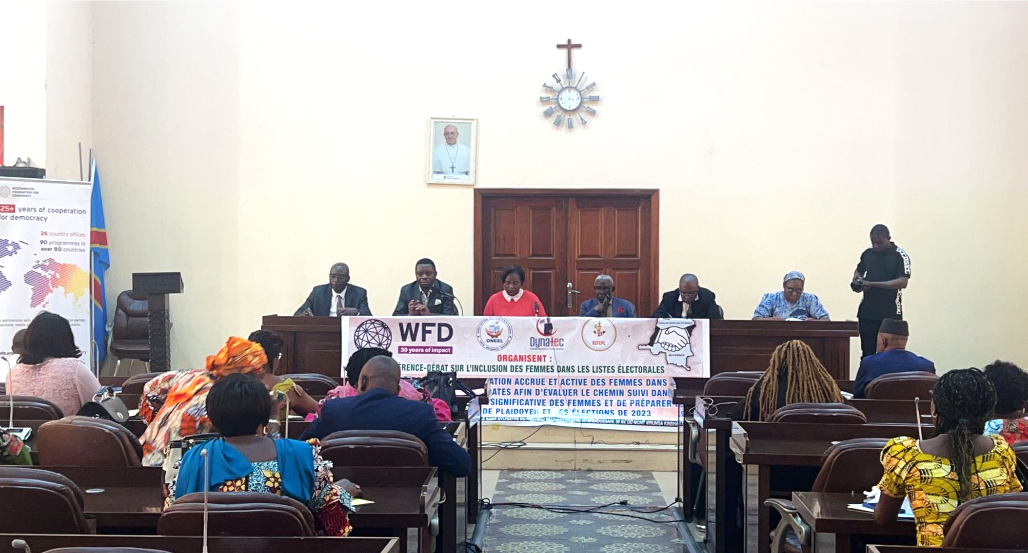 people sitting in a podium looking at others sitting in a meeting