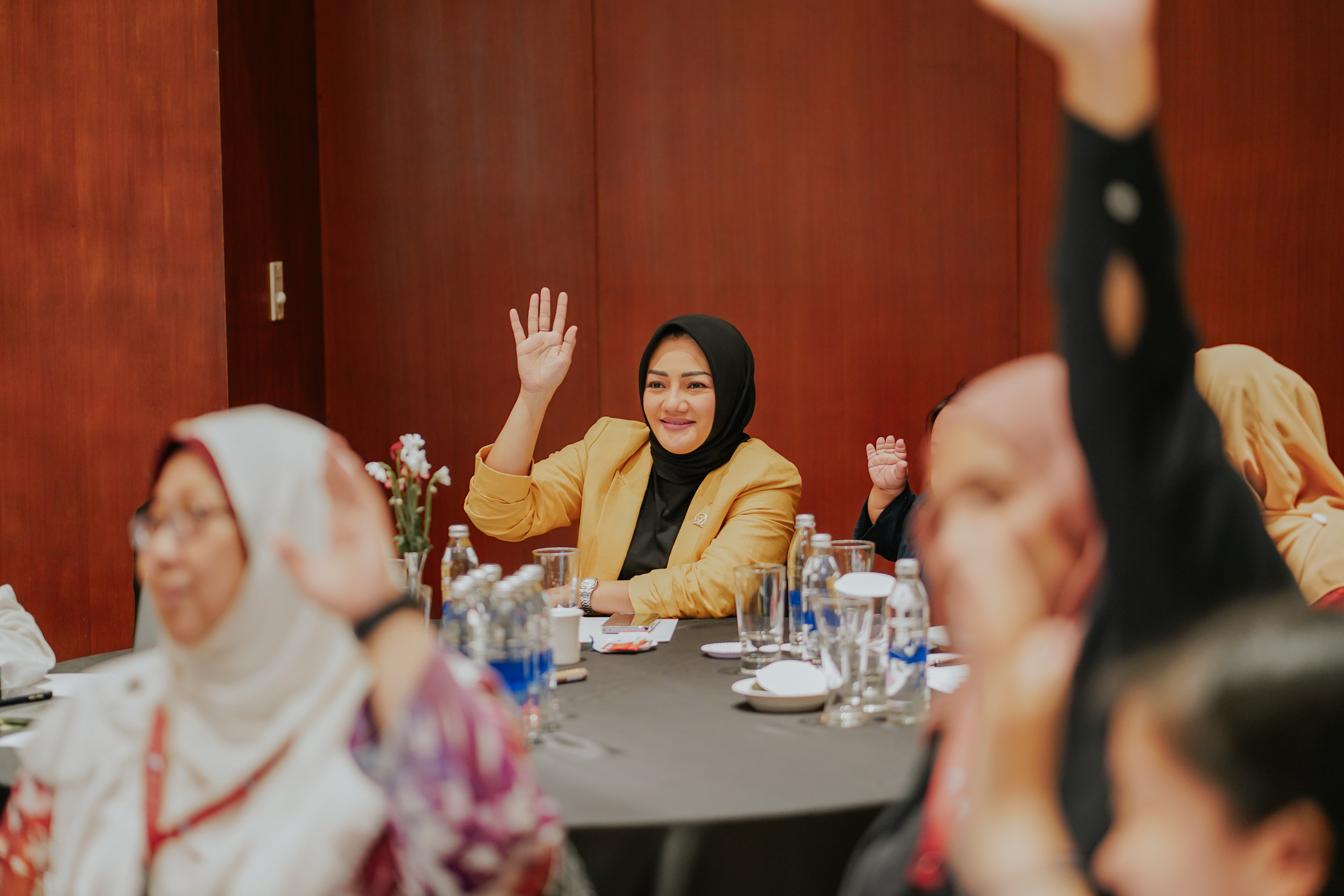 Women sitting at tables raising their hands