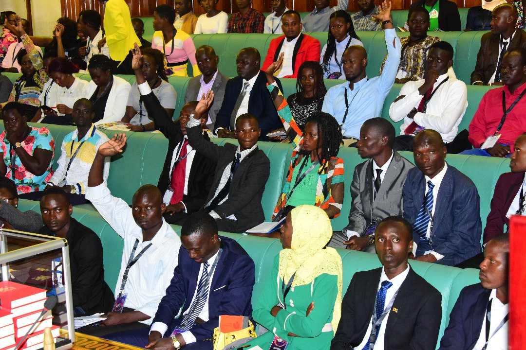 Young leaders in Uganda in the Ugandan Parliament lifting hands up