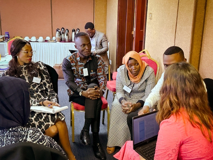 A group of young people in Kenya sitting in a circle, discussing