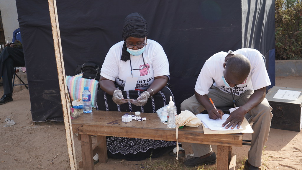 Two election officials sitting side by side at a table working on paper