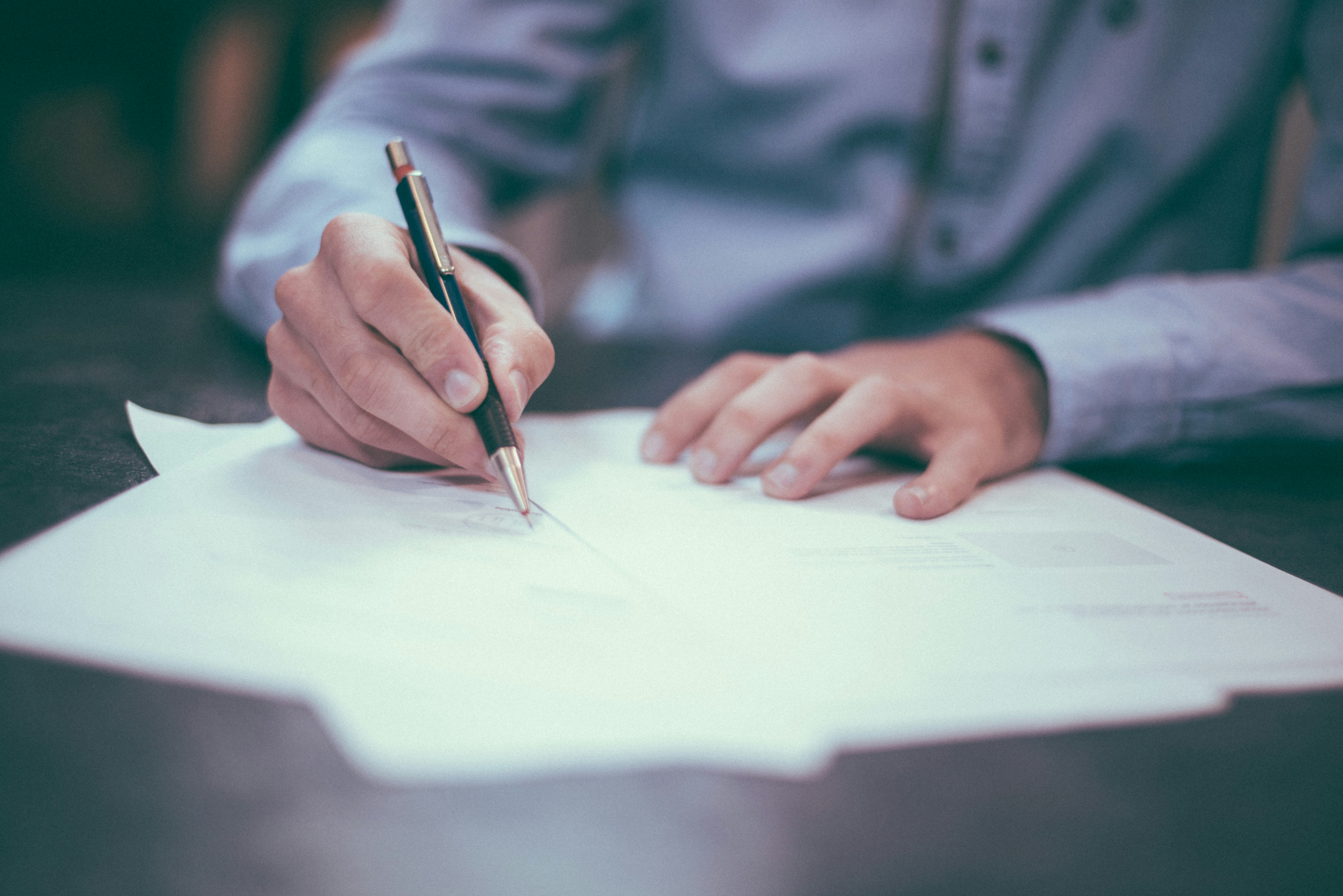 A person wearing grey shirt writing