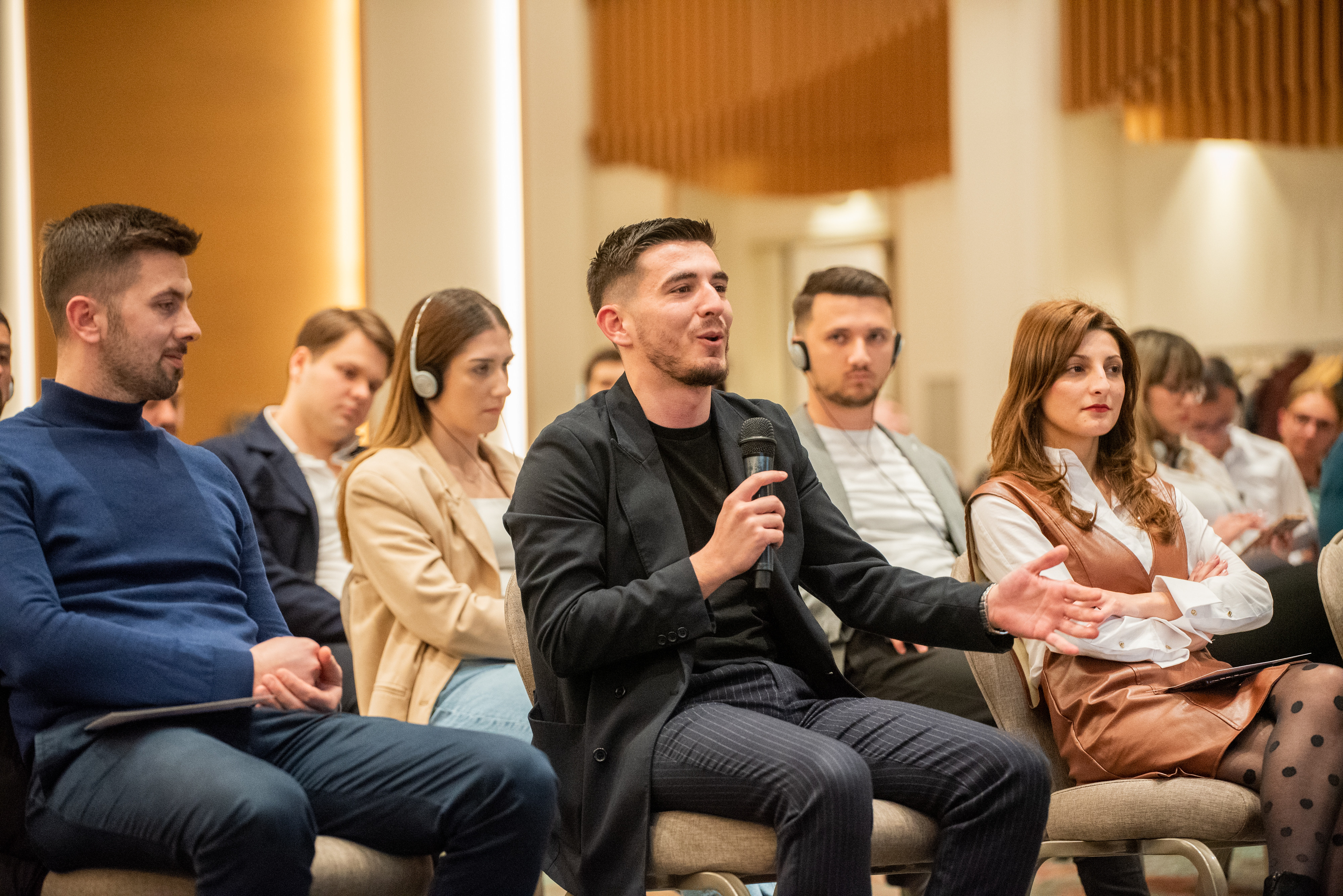 A person speaking using a mic while sitting around others