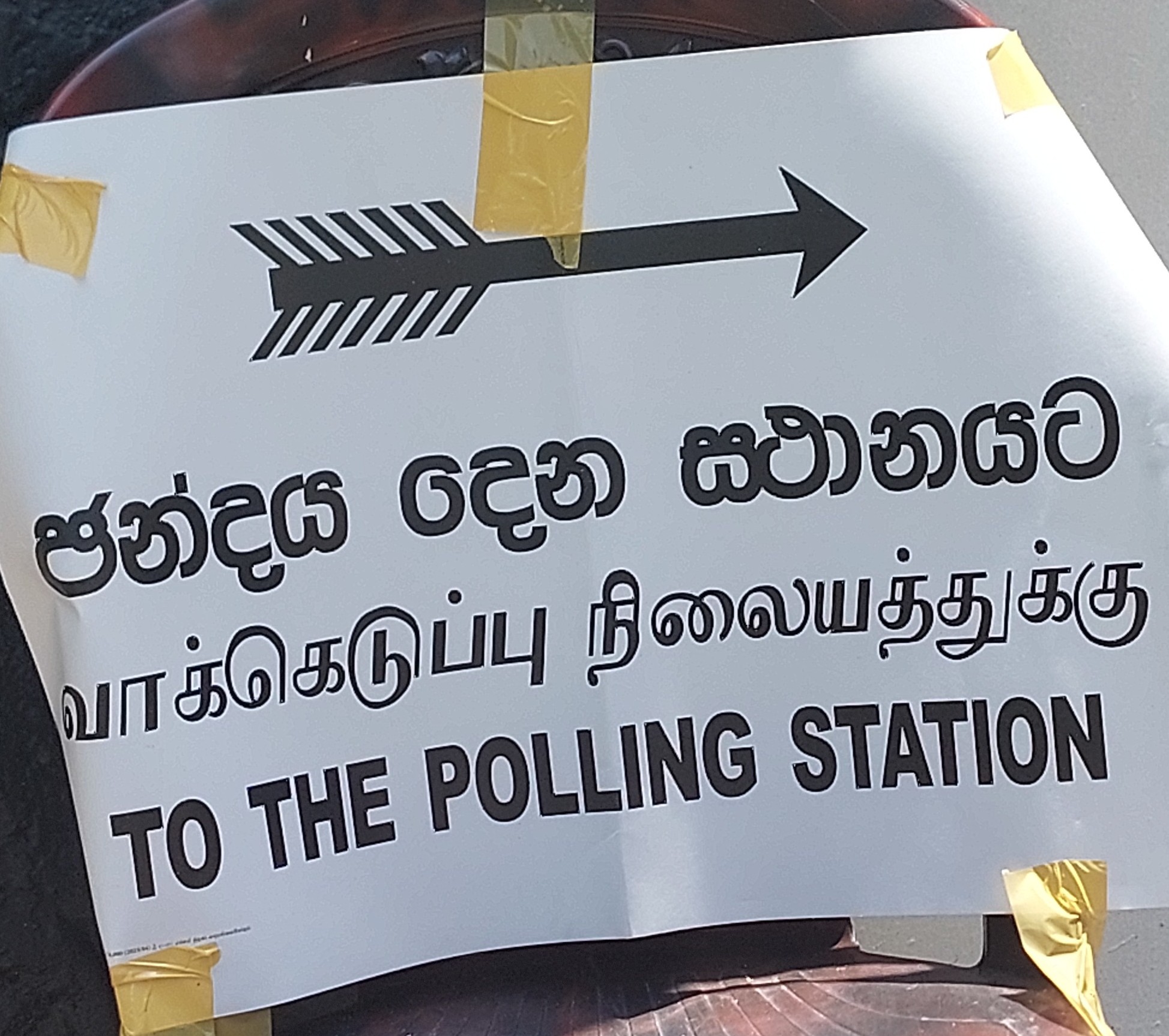 A trilingual sign with an arrow that points to the polling station