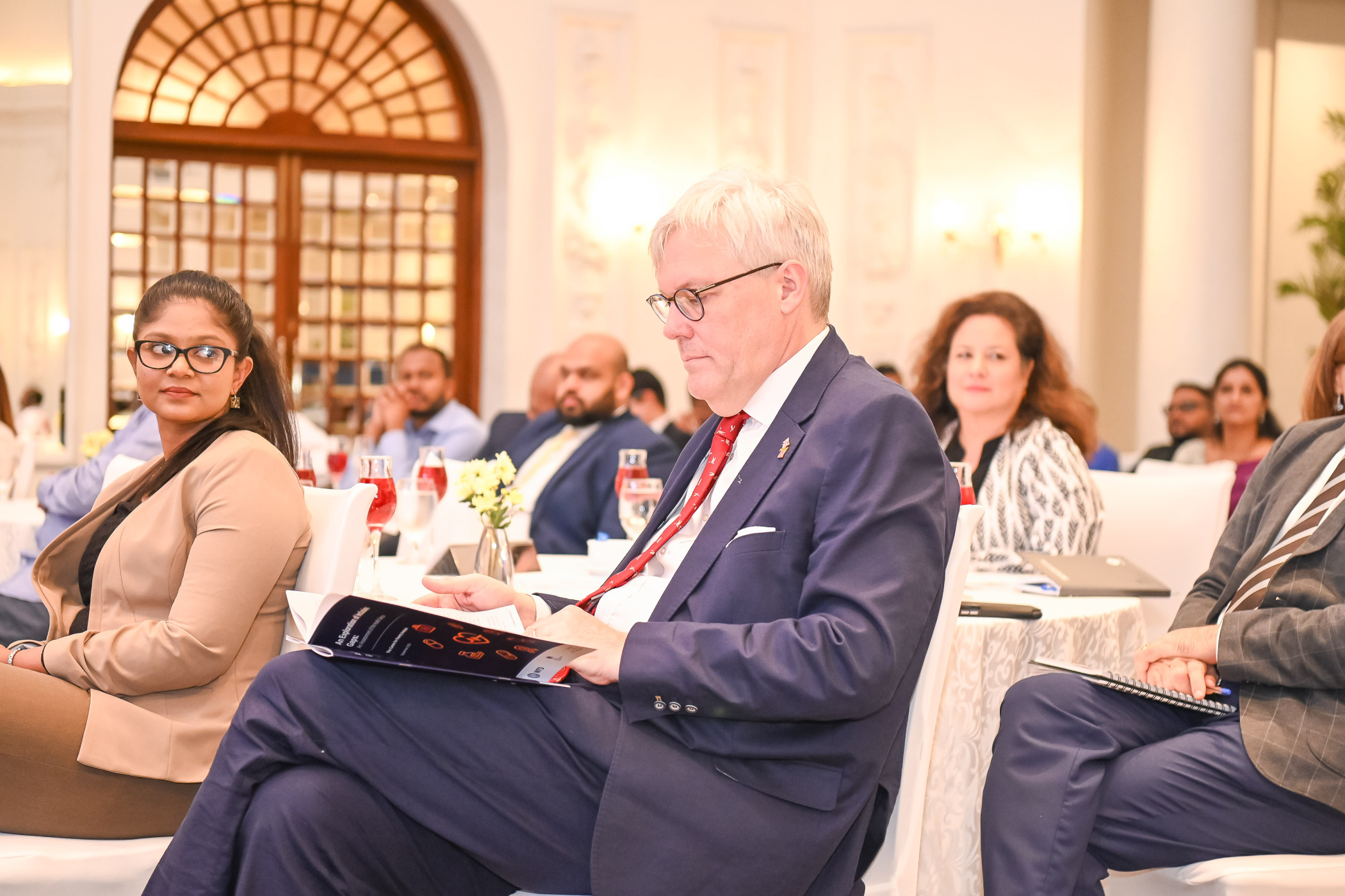 A man in a meeting reading a report while sitting