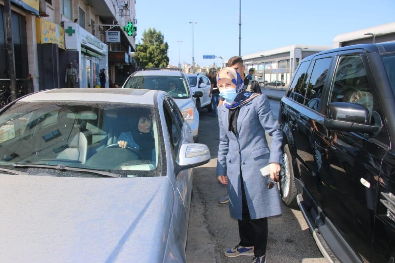 A woman talking to someone in a car while 