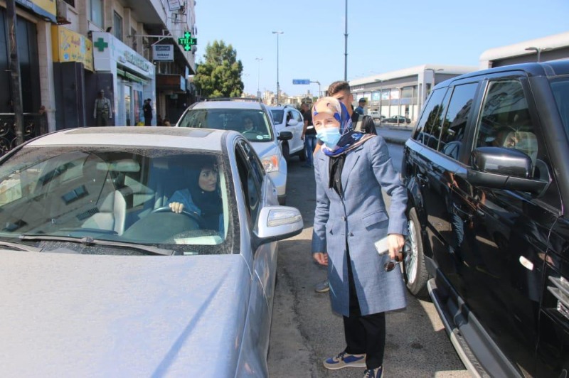 A woman standing by the side of a car 