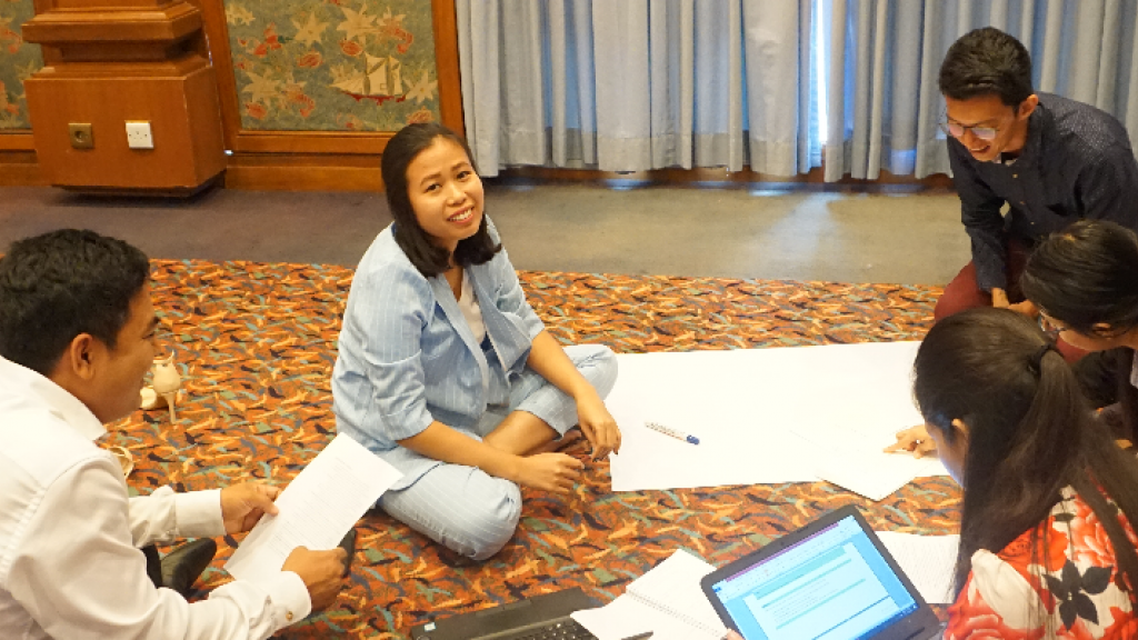 People sitting round a piece of paper working together