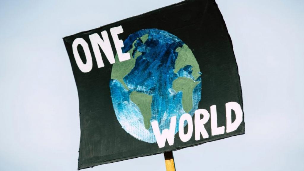Placard written one world with the map of the globe in between