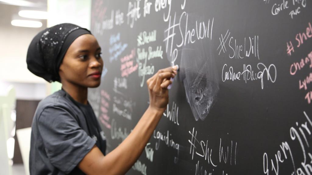 A delegate signs the #SheWill wall at the Girls' Education Forum, London, 7 July 2016