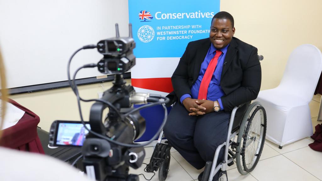 A man being interviewed in front of a Conservatives banner