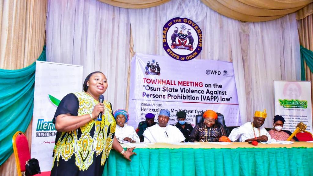 A woman speaking into a microphone at a town hall meeting in Nigeria