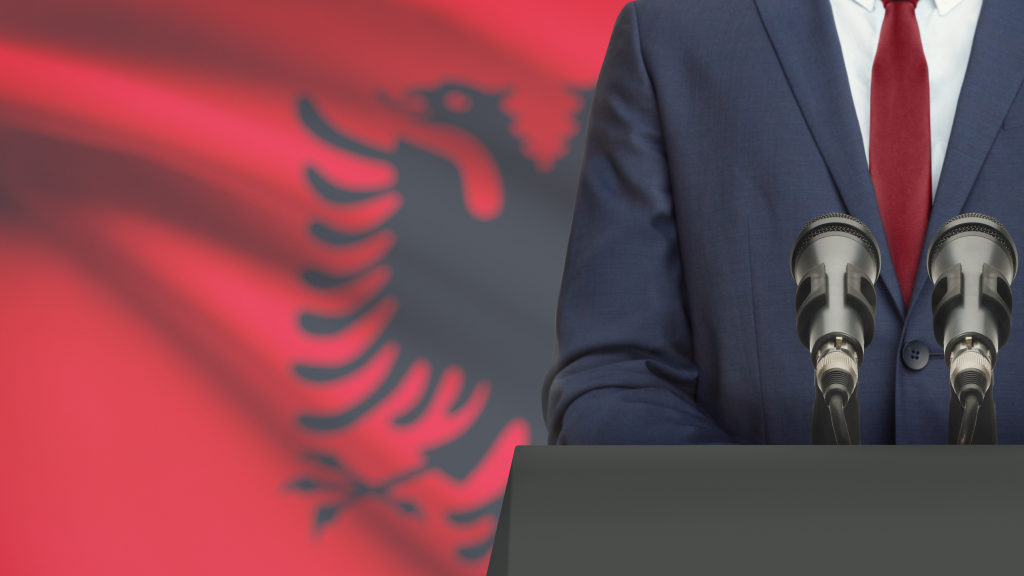 person standing in front of a microphone, albanian flag