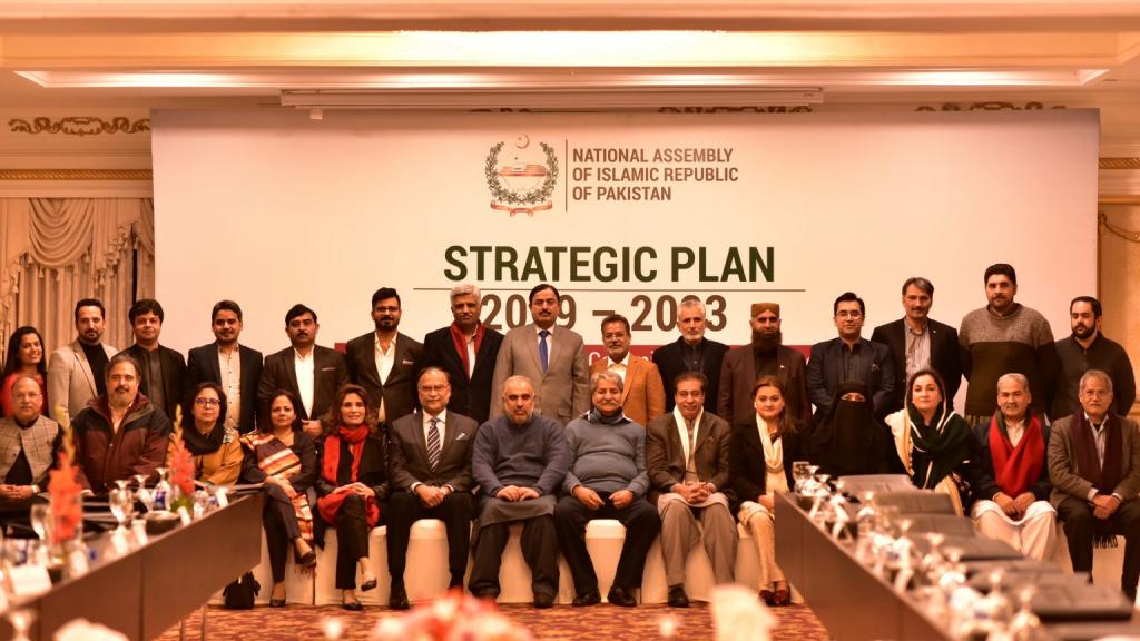 People sitting in rows in front of a sign saying strategic plan