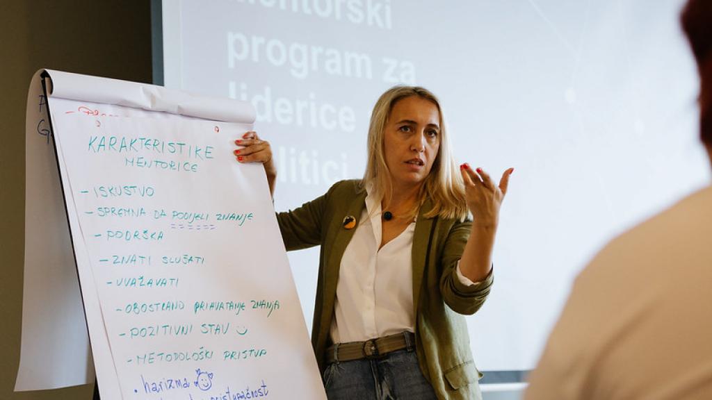 A woman standing next to a flip chart with writing in local language