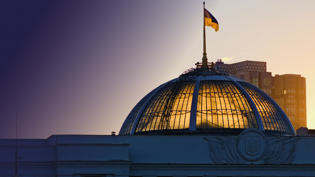 The sun coming through the dome of the Parliament of Ukraine, with the Ukrainian flag flying above 