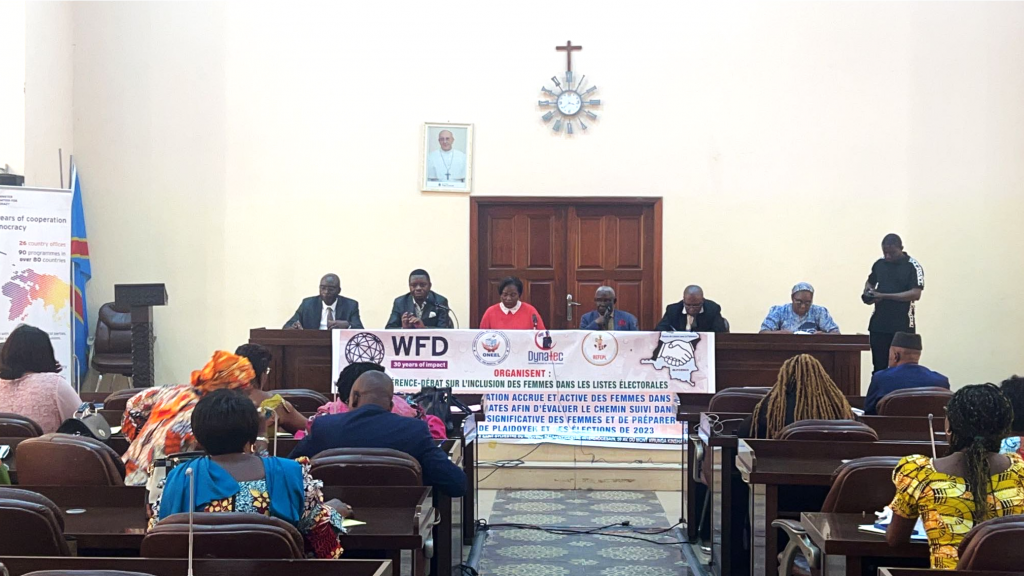 people sitting in a podium looking at others sitting in a meeting