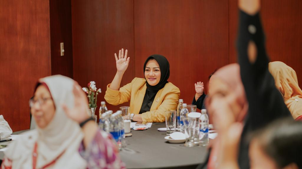 Women sitting at tables raising their hands