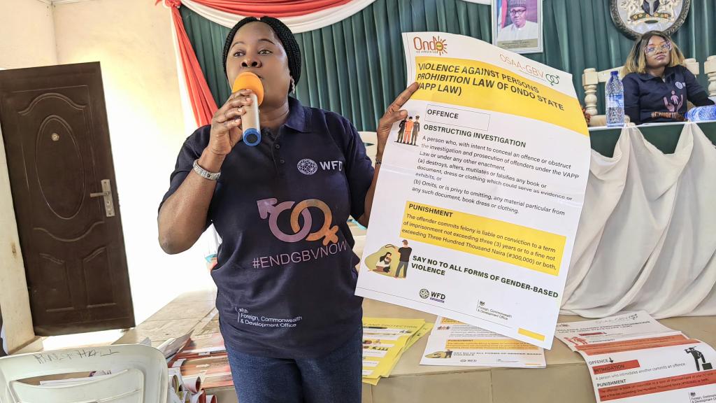 A woman holding a an advocacy paper while speaking on a microphone