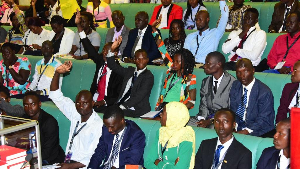 Young leaders in Uganda in the Ugandan Parliament lifting hands up