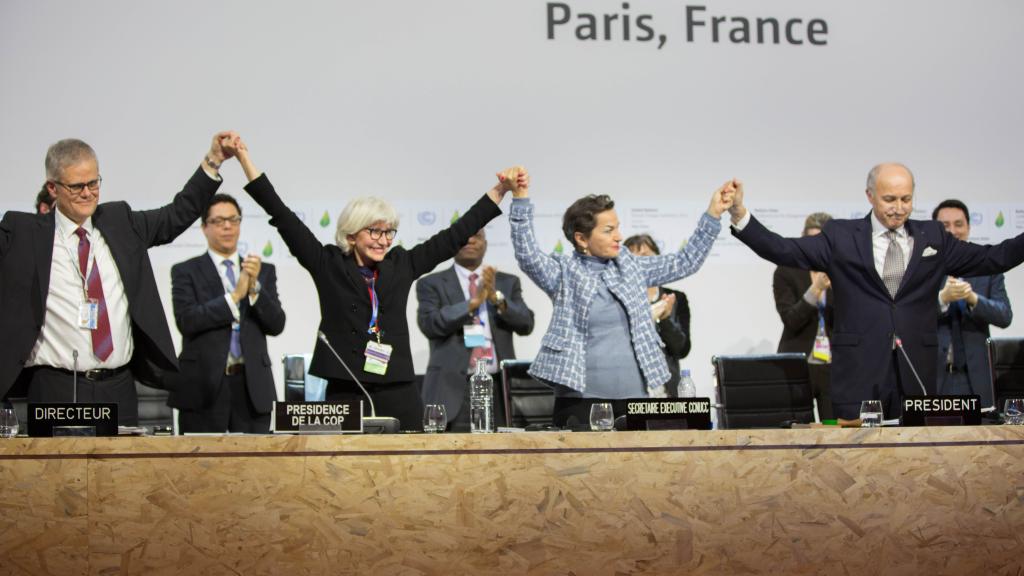 Delegates at the Paris Climate Conference standing holding hands in the air