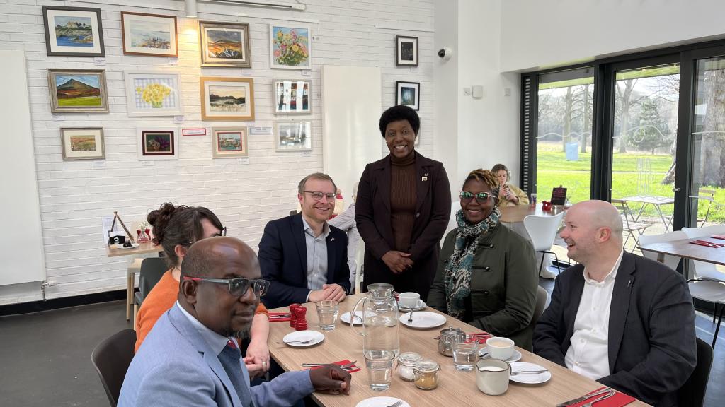 People sitting with one standing while they take tea