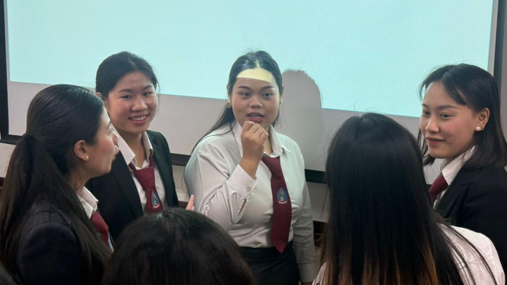 A group of young female students in uniform stand in a circle talking. 