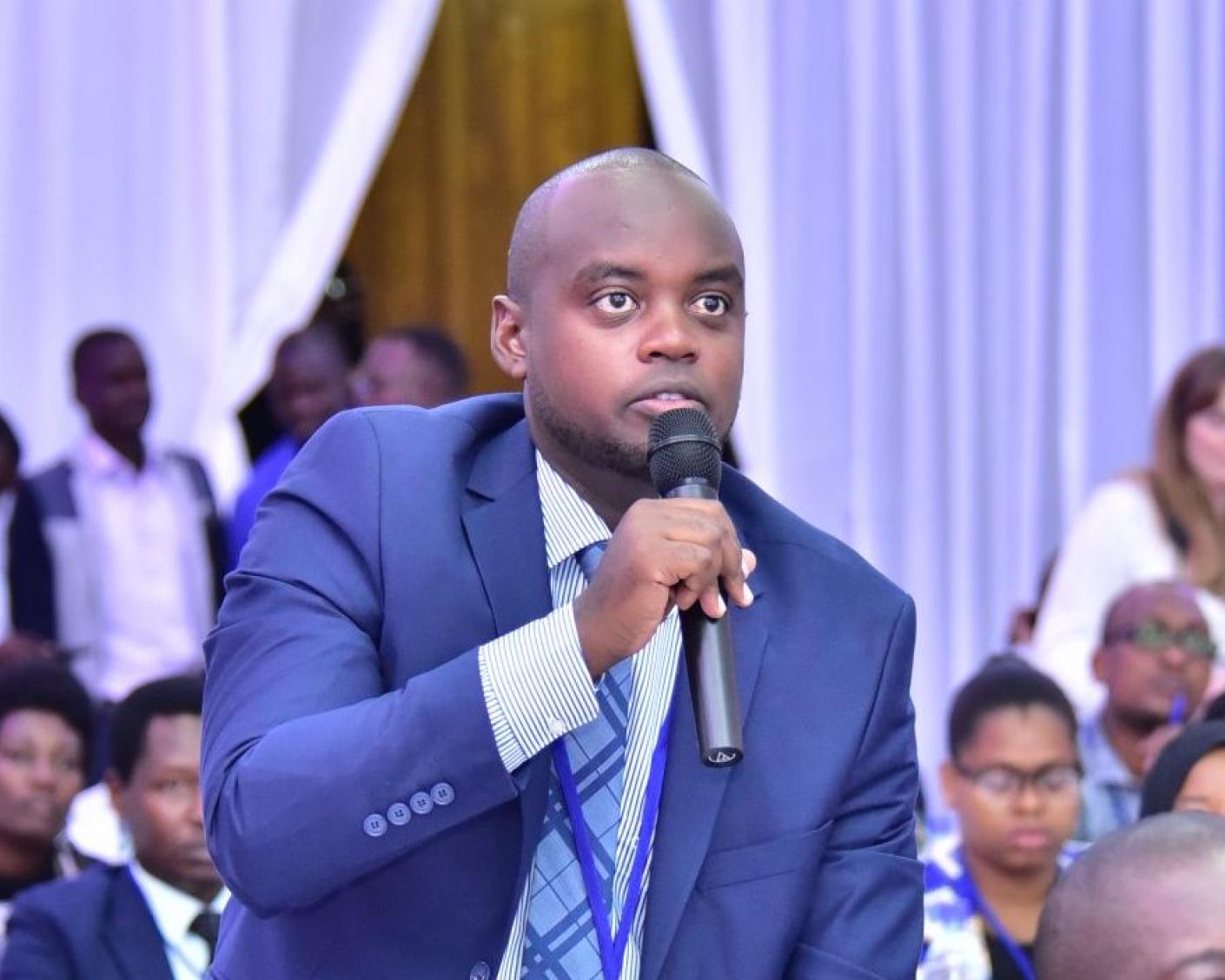 A person among a group of people in meeting holding a microphone
