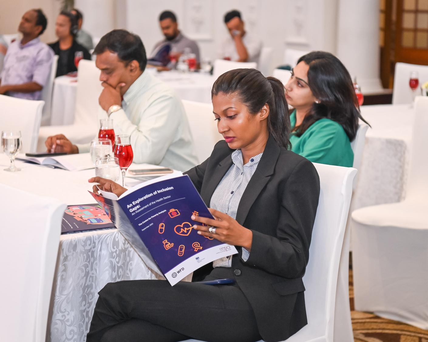 An woman sitting at a table reads WFD research on access to health services in Sri Lanka
