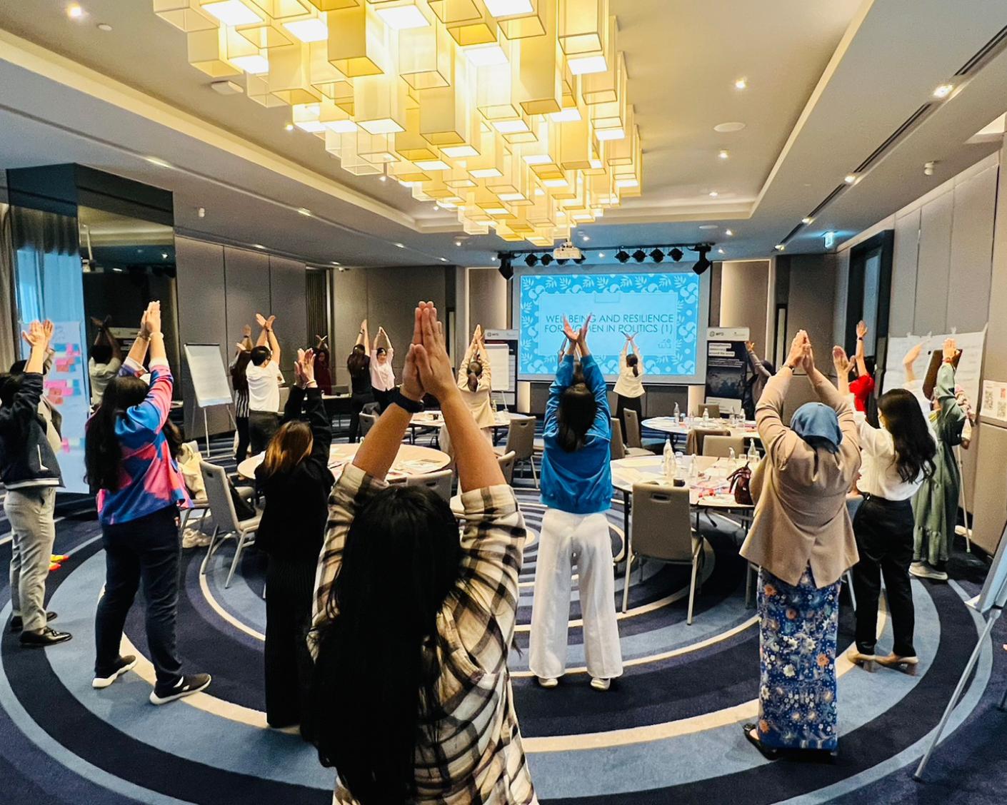 A group of participants raising their hands with palms together at a workshop on gender justice for women candidate MPs in Thailand in February 2023. 
