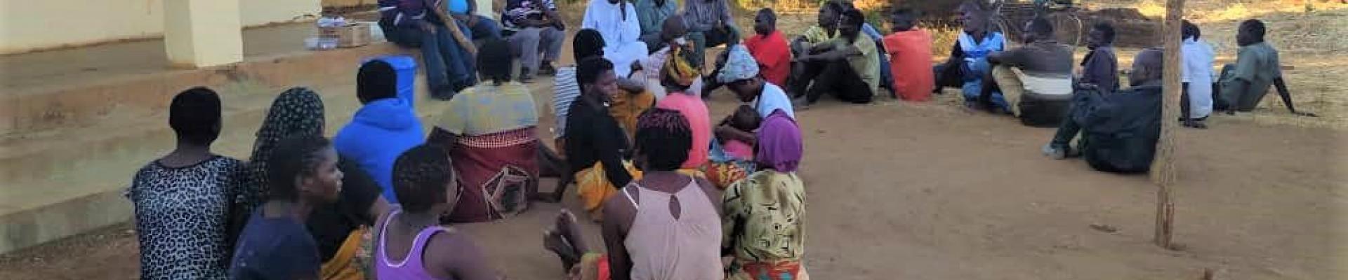 A group of people sitting on the ground deliberating
