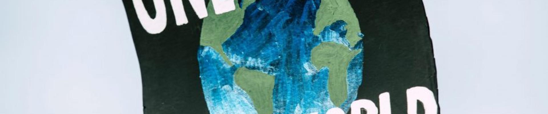 Placard written one world with the map of the globe in between