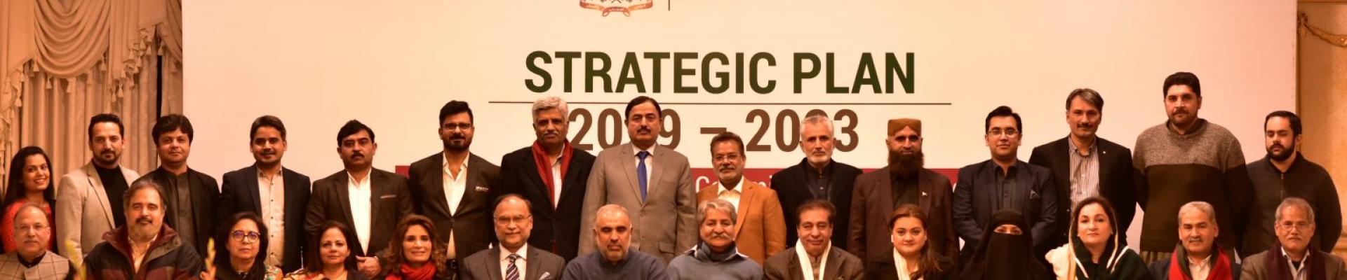 People sitting in rows in front of a sign saying strategic plan