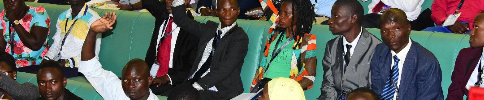 Young leaders in Uganda in the Ugandan Parliament lifting hands up
