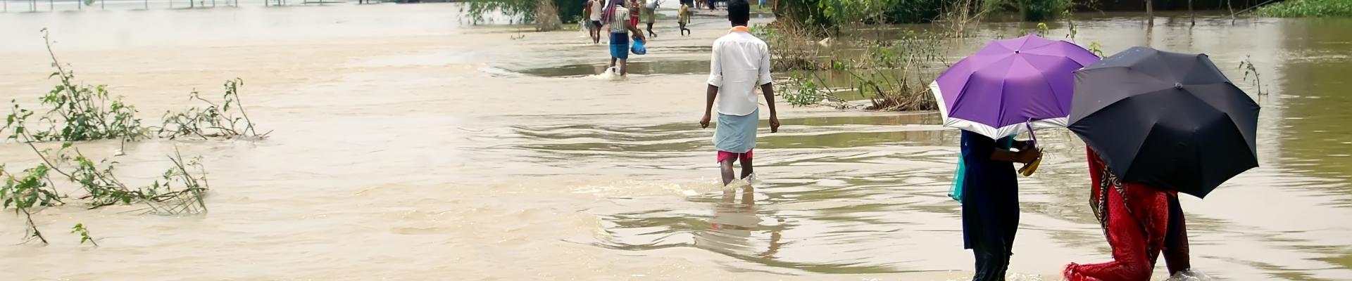 People walking through brown flood waters