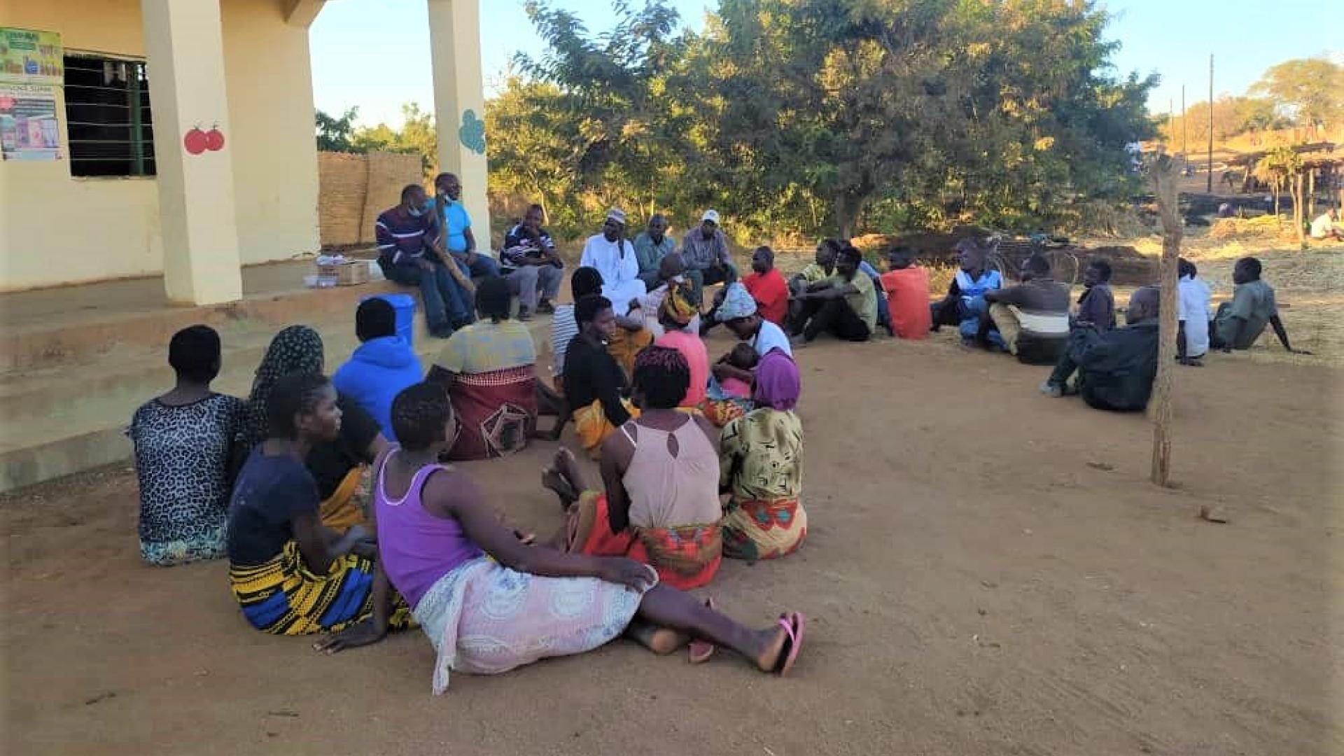 A group of people sitting on the ground deliberating