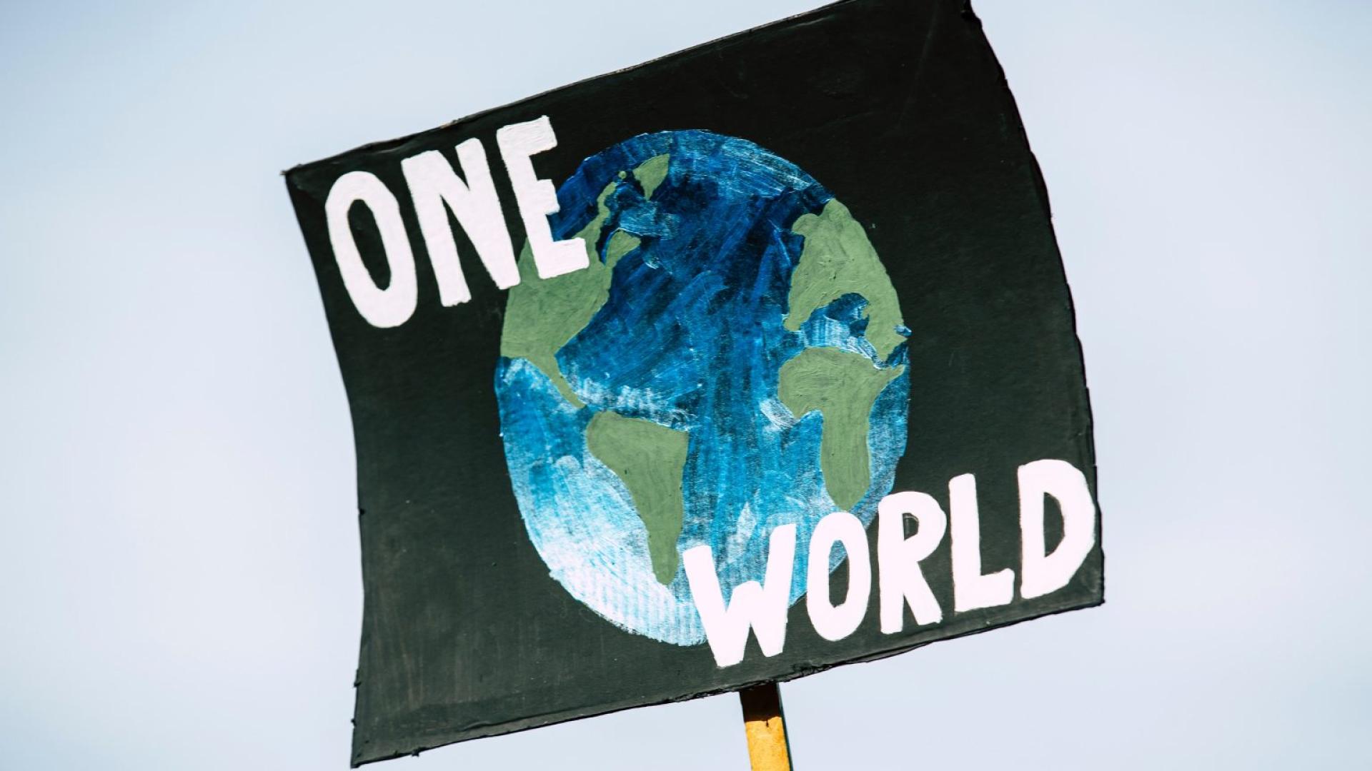 a protest banner reading one world