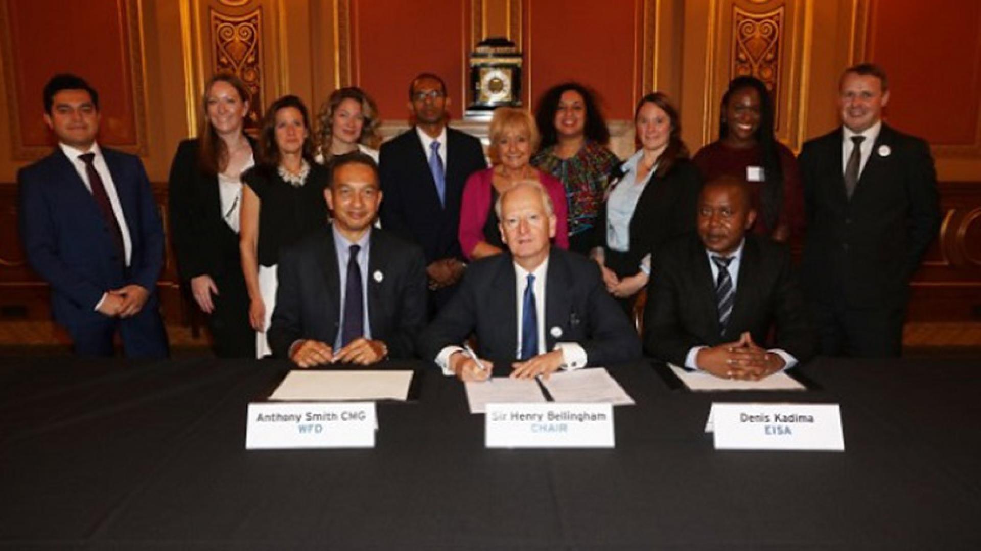 Three people sitting as a group is standing behind them