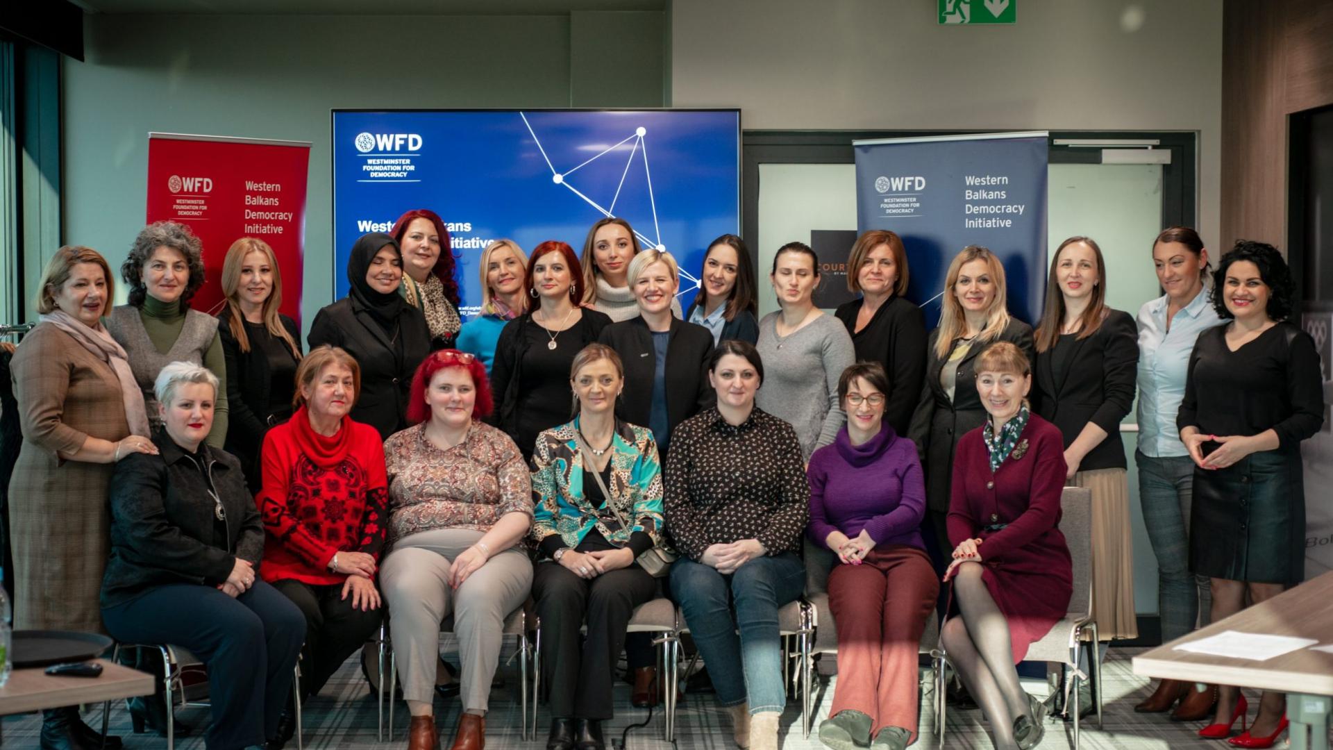 A group photo of programme participants smiling seating in rows