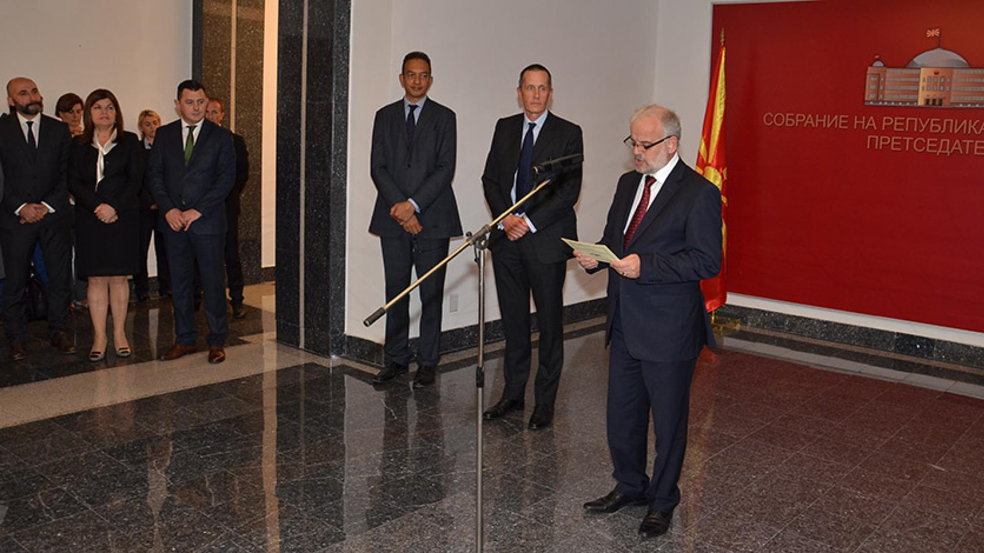 A man giving a speech while other people stand on the side