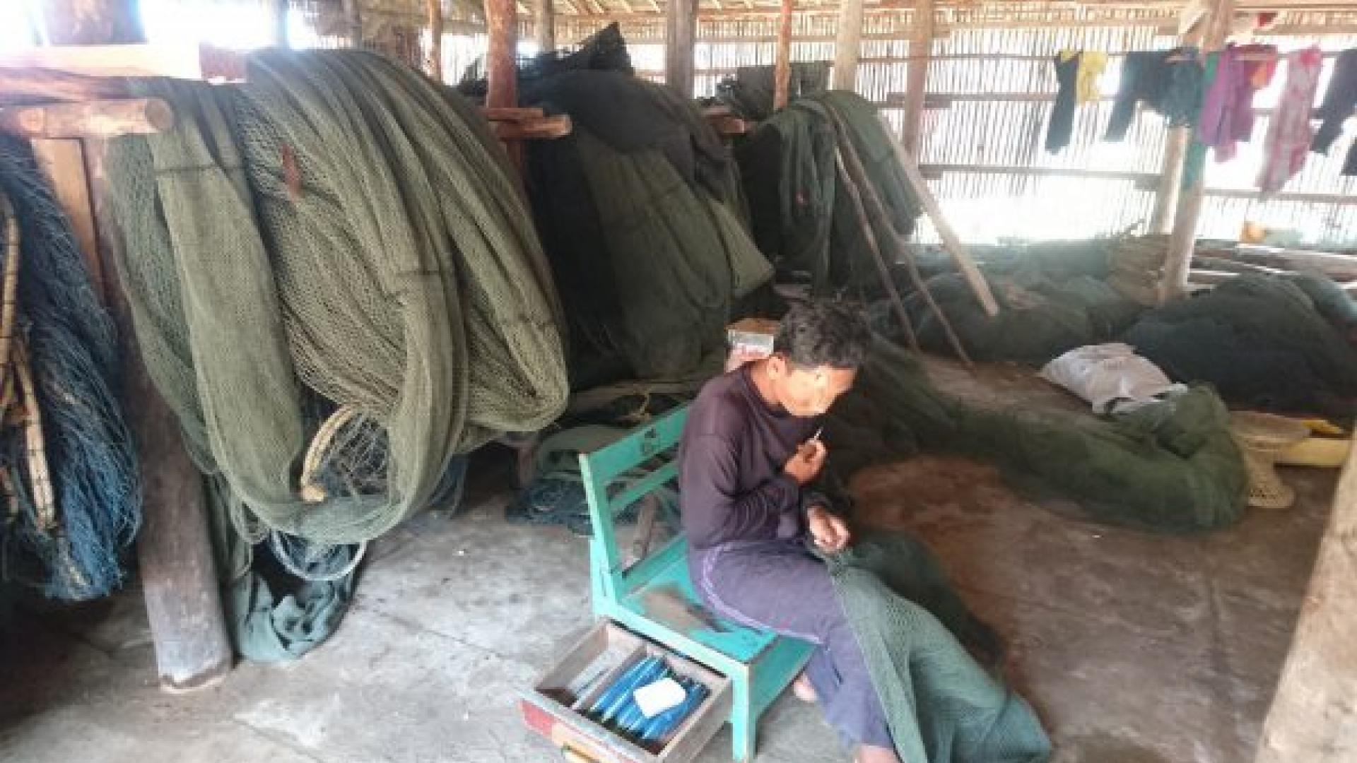 A fishery worker sewing nets that are used for shrimp fishing